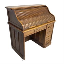 Early 20th century oak roll-top desk, the tambour enclosing pigeon holes and small drawers, the base fitted with slide, a single long drawer and three smaller drawers
