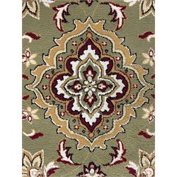 Turkish Sincerity Royale green ground rug, the field decorated with a central floral medallion surrounded by scrolling floral motifs in shades of cream, beige, and burgundy, spandrels filled with matching floral designs, the border featuring a series of floral patterns on a cream ground, finished with green edges