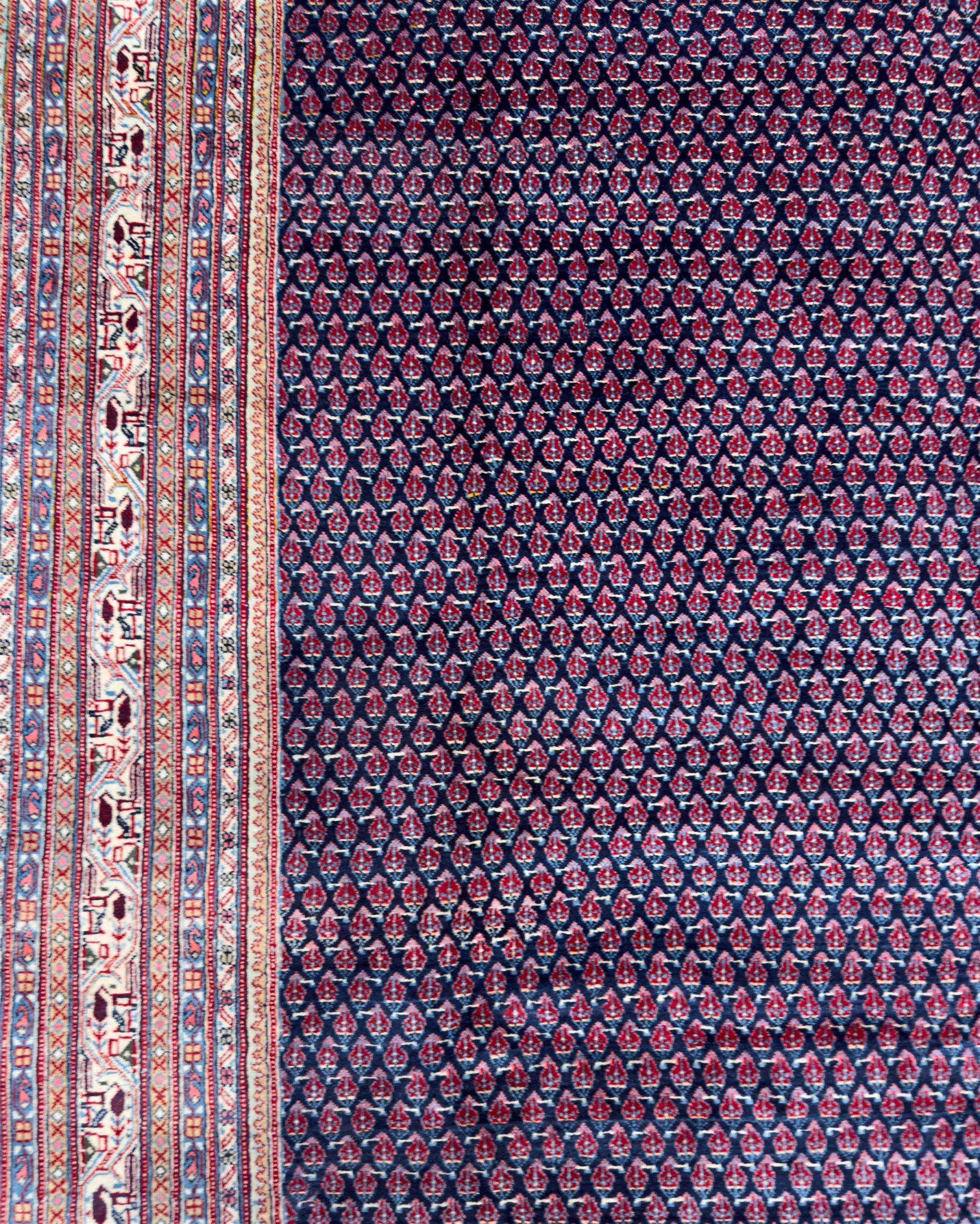 Northwestern Persian Bottehmir hand-knotted carpet, dark indigo field with an all-over design of boteh motifs arranged in diagonal rows, framed by multiple borders, main ivory border with stylized floral sprays between narrow geometric guard stripes, 362cm x 268cm