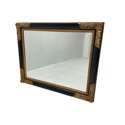 Gilt and ebonised framed wall mirror, the frame decorated with foliage and flower heads, foliate moulded slip, bevelled plate 