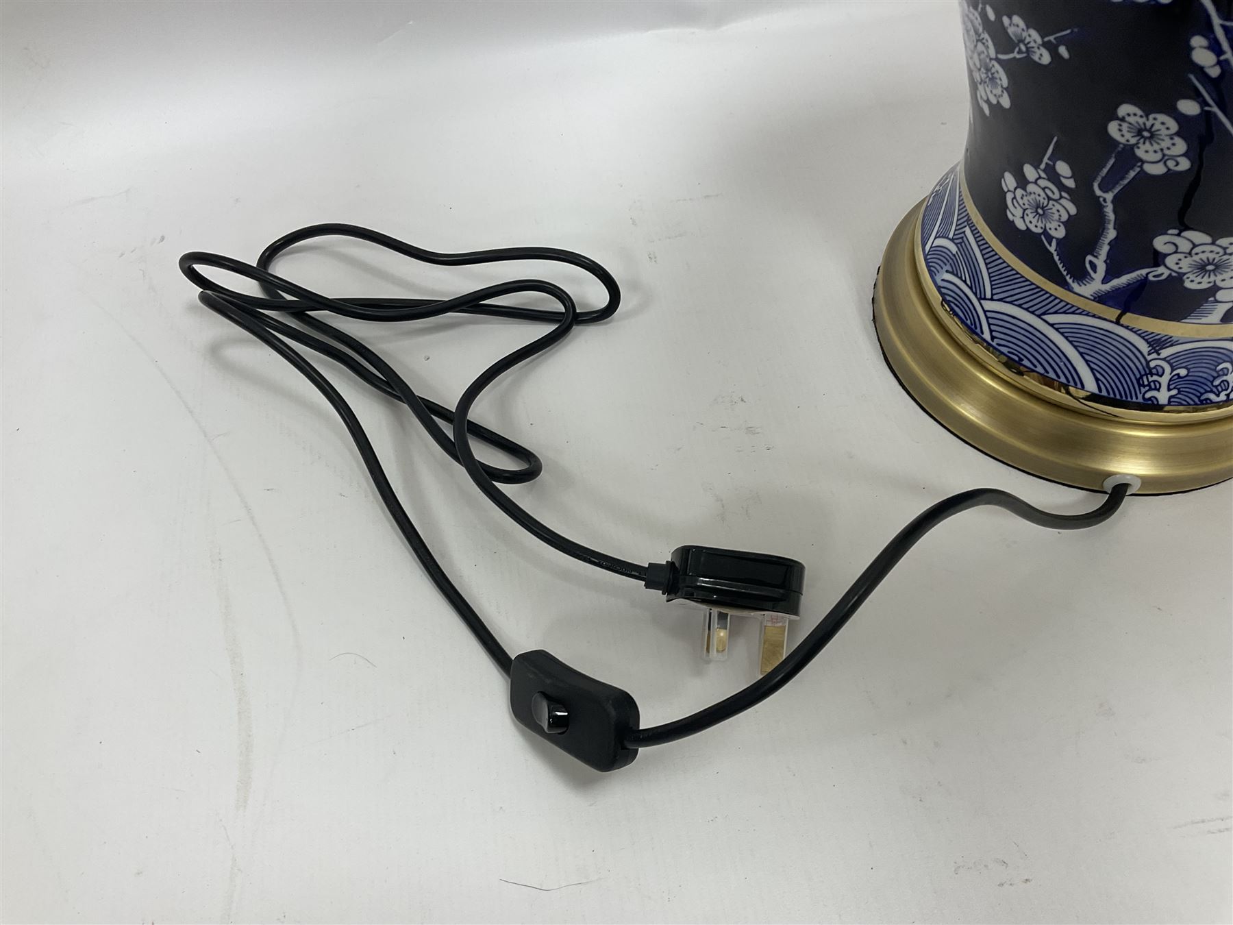 Pair of blue and white table lamps, each of baluster form, decorated with prunus blossom, within stylised borders, raised upon circular gilt base, excluding fittings H48cm