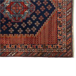 North West Persian Heriz hand-knotted rug, indigo field with three central stepped geometric medallions arranged vertically, enclosed by angular spandrels and multiple geometric borders in shades of madder red, ivory, and pale blue, with cotton fringe ends  
