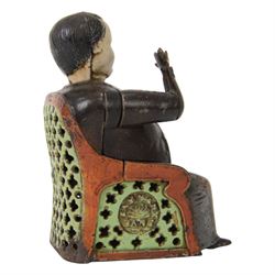 Late 19th century American cast iron Tammany mechanical money box, modelled as a suited gentleman with yellow waistcoat seated in a red and green chair, with two patent marks for Dec 23rd 1873 and June 8th 1875, H14cm