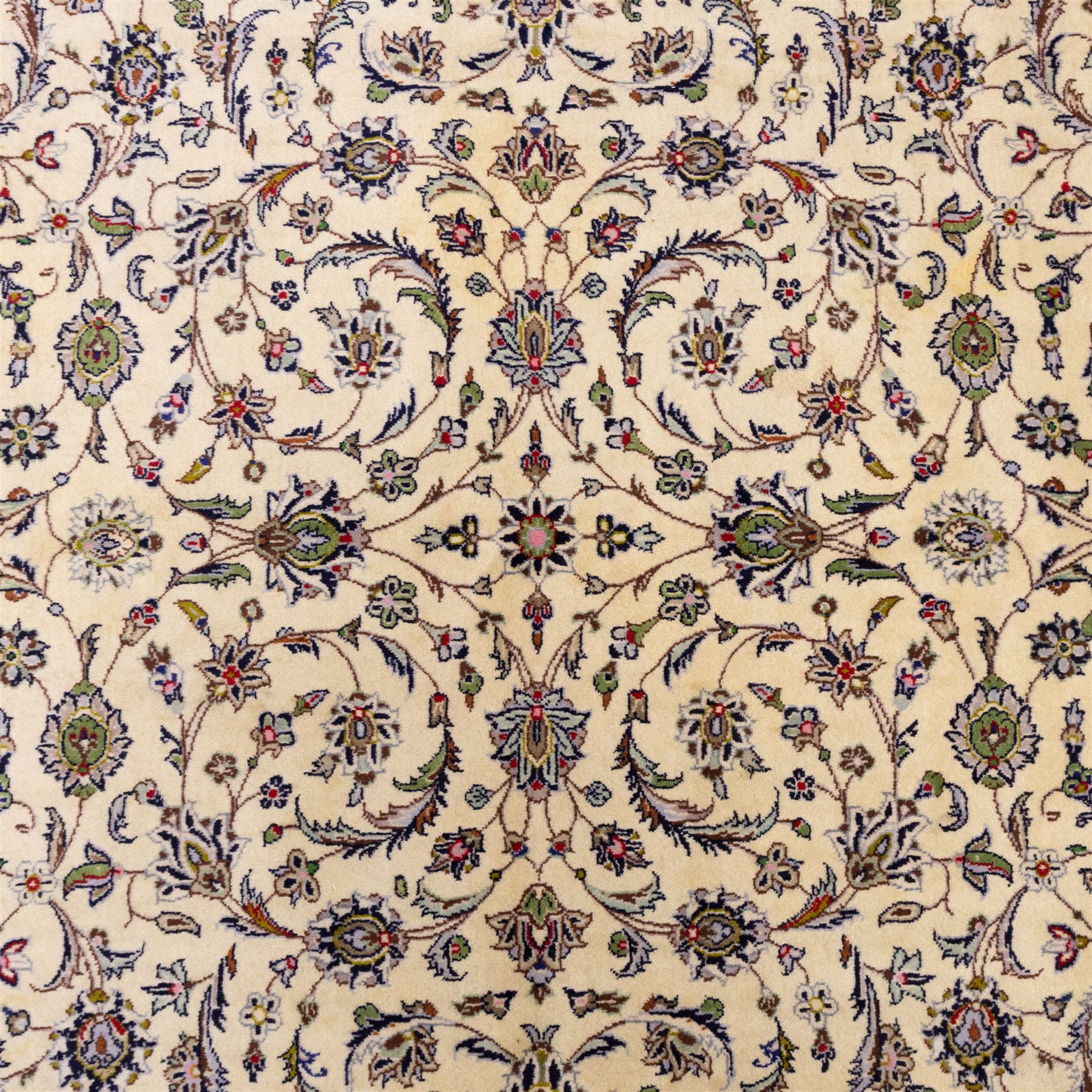 Central Persian Kashan hand-knotted carpet, ivory field densely decorated with an all-over design of scrolling floral vines and palmettes, framed by multiple borders with continuous floral meander and rosette motifs, in a palette of indigo, ivory, soft blue, sage green, rose and ochre tones, with cotton fringe ends 