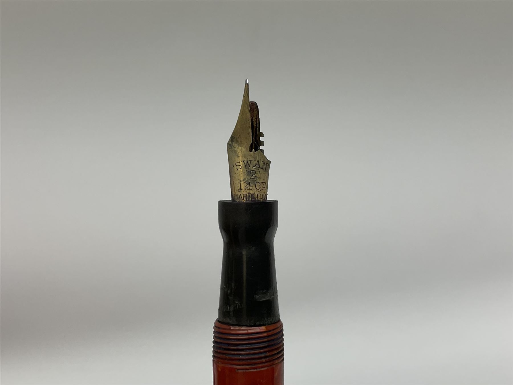 Vintage Swan Mabie Todd lever fill fountain pen in coral red, the nib a/f marked 14K, together with two further vintage Swan Mabie Todd fountain pens, the first example with lever fill, the other leverless, each with black body, one with nib marked 14ct, (3) 