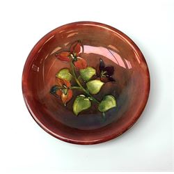 A Moorcroft flambe dish, circa 1950, decorated in the Bougainvillea pattern, marks beneath obscured by glued on fabric hanger, D19cm. 