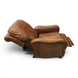 Art Deco style brown leather reclining armchair, scrolled arms with brass studded trim, reclining foot rest and back, fixed back and loose seat cushion,