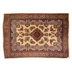 Central Persian Kashan hand-knotted carpet, cream ground, with a central lobbed floral bur...