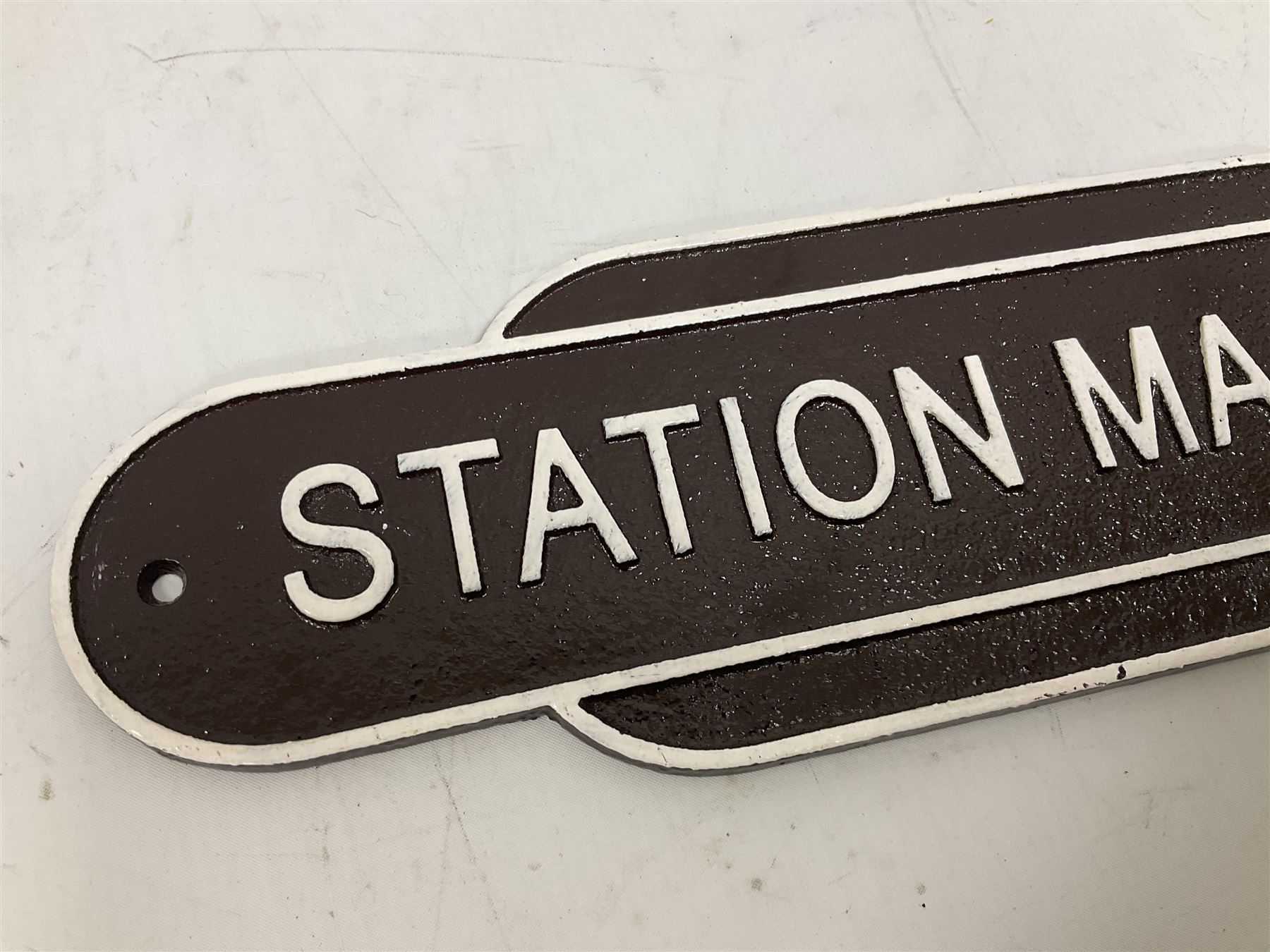 Cast iron Station Master wall plaque on a brown ground, L39cm