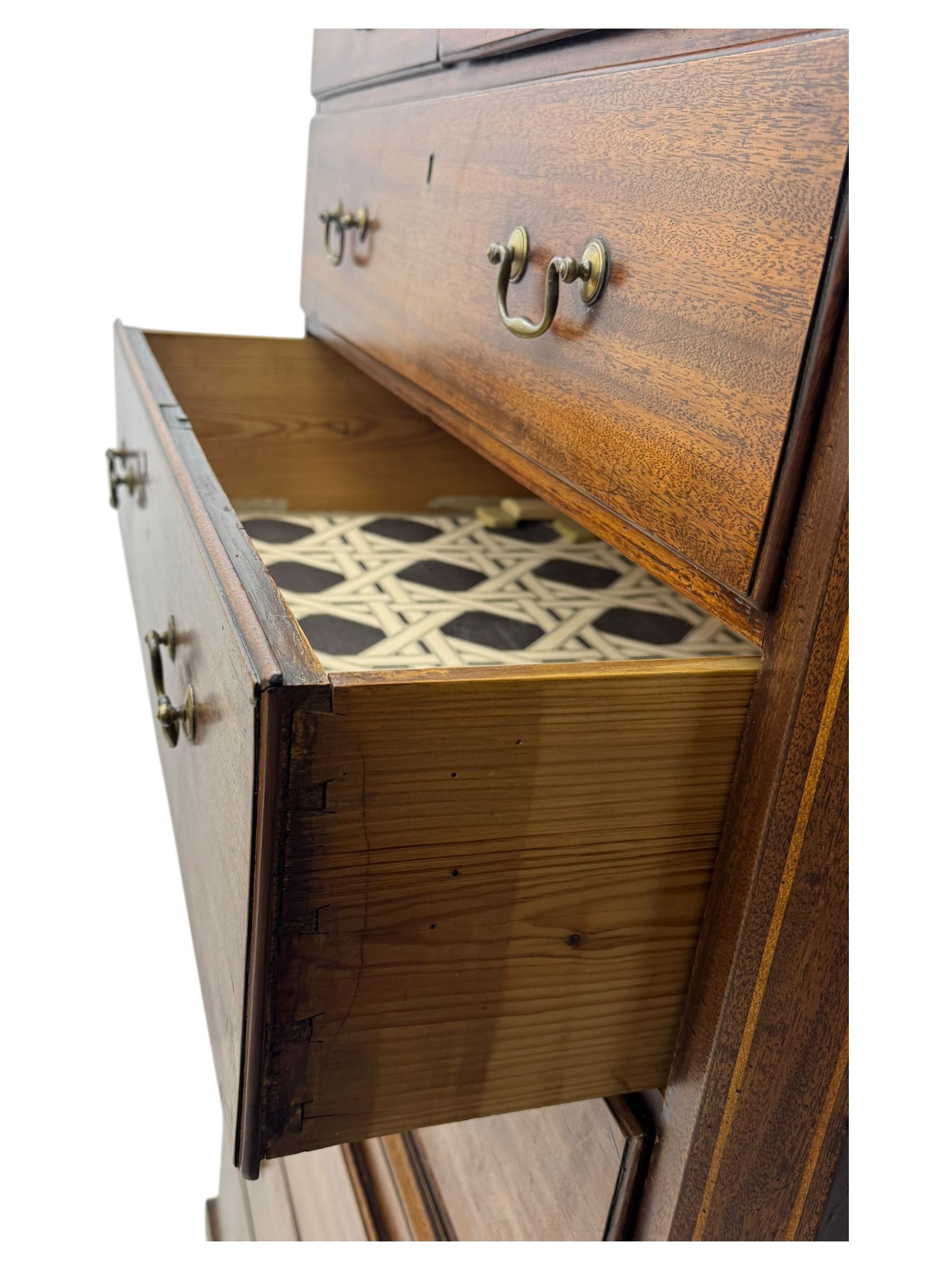 George III mahogany chest on chest, the upper section with two short over three long drawers with swan neck handles flanked by canted corners, inlaid with boxwood stringing below a dentil cornice. The lower section with three long drawers, supported on bracket feet 