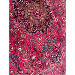 North East Persian Meshed fuschia ground carpet, the floral pole medallion flanked by banners with palmette motifs, surrounded by scrolling and interlaced branches of foliage, the border with bands of Boteh motifs, decorated with repeating stylised plant and flower head designs
