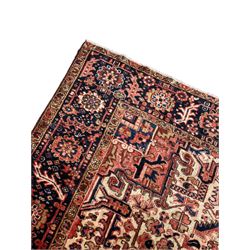 Persian Heriz red ground carpet, large stylised pole medallion surrounded by Pitrak motifs, indigo ground border decorated with stylised flower heads and trailing leafy branches, within floral pattern guard stripes