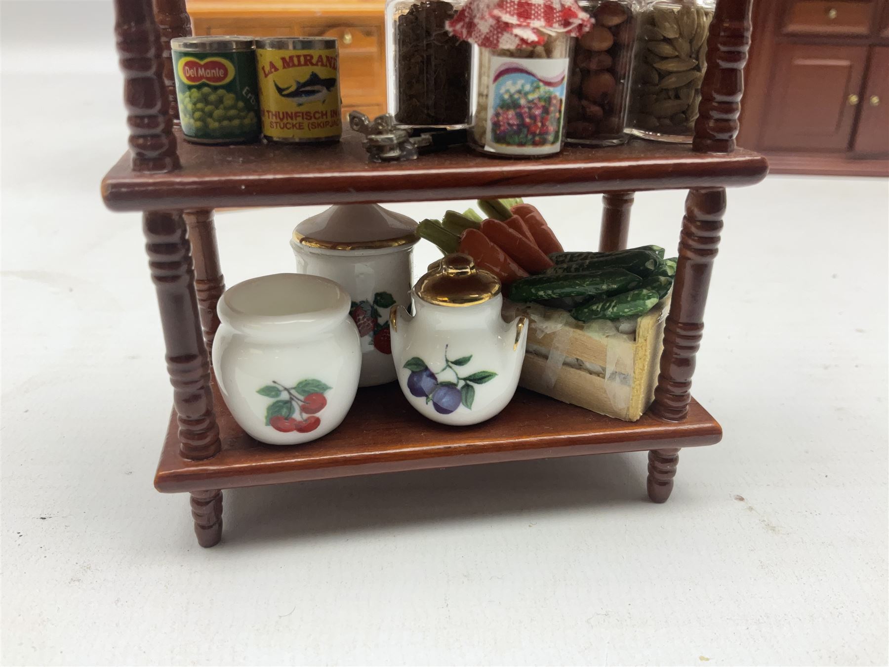 Collection of kitchen and bedroom dolls house furniture, to include two units housing Reutter, Germany ceramic plates, tea wares and accessors comprising one example with a Belfast sink with various pots and pans and jars, the second housing various baking equipment, two dressers, baking table, shelf unit housing various jars of herbs and basket of produce, fridge, and lace and jacquard bedroom suite including bed, pair of bedside tables, dressing table and ottoman