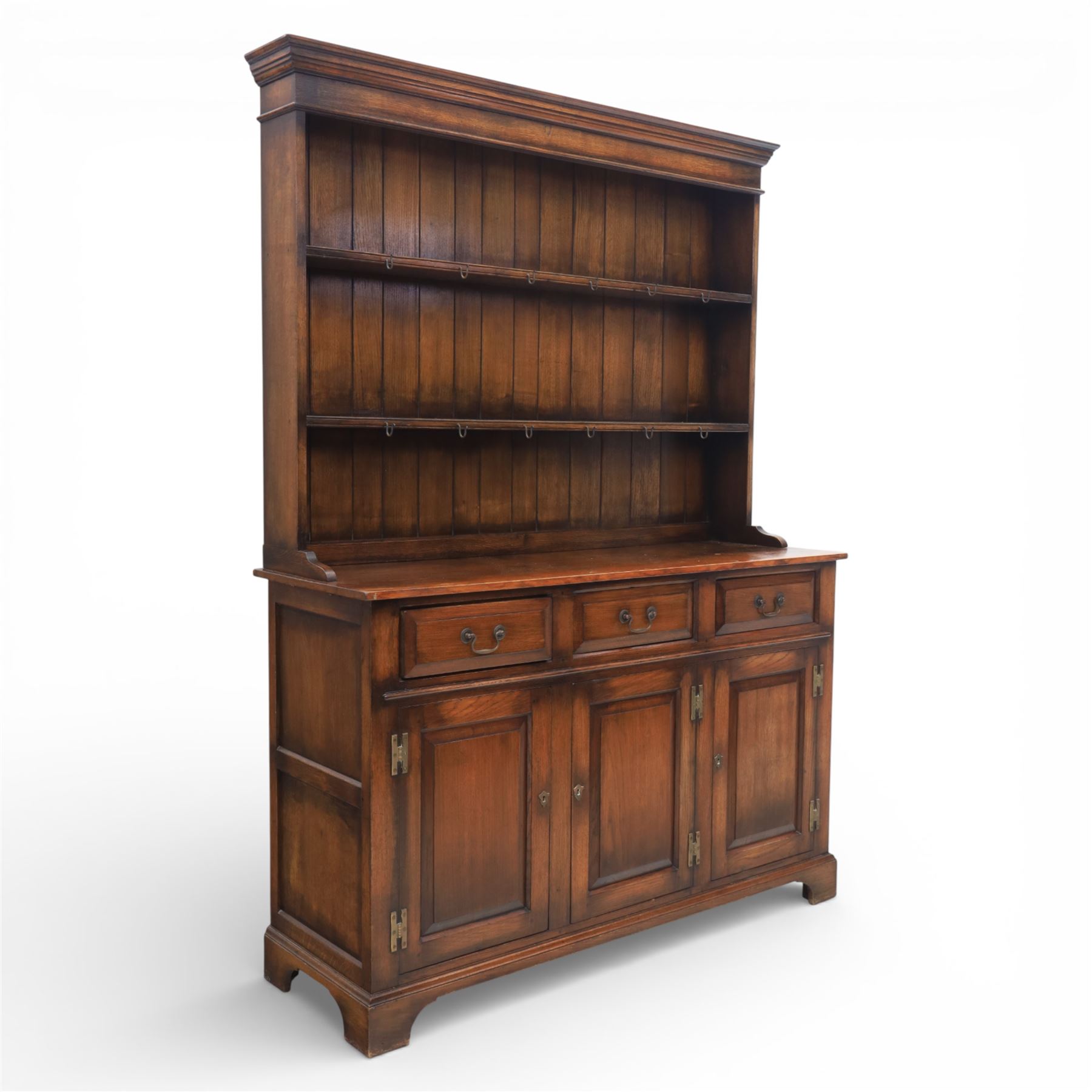 Georgian style oak dresser, the moulded cornice above two open plate racks, upon base with rectangular top above an arrangement of three frieze drawers fitted with brass swan neck handles, and three panelled cupboard doors, upon bracket feet
