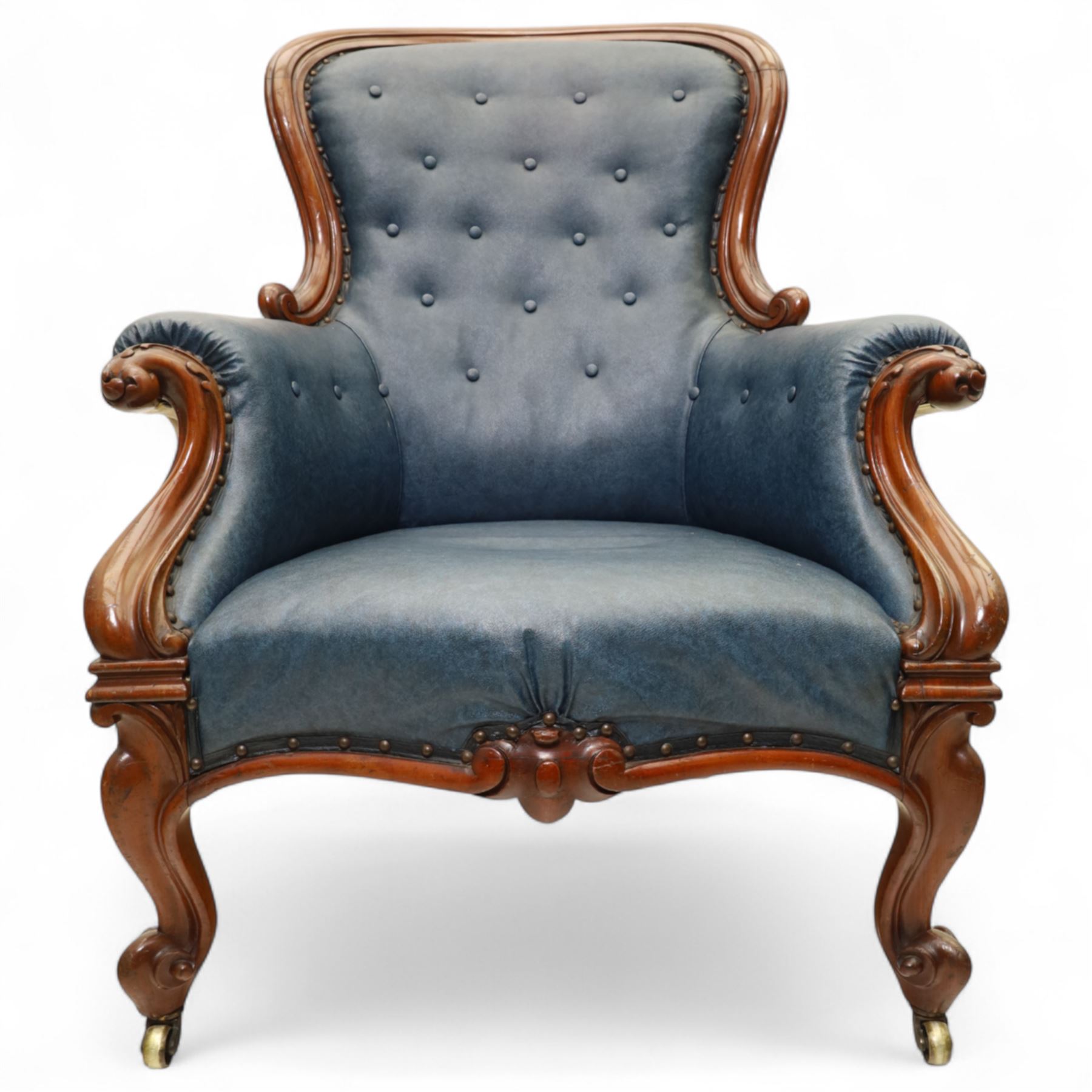 Fine pair of mid-19th-century mahogany library armchairs, carved frame with balloon-shaped back with scrolled ends, rolled wide arms, ending in a scrolled volute above a serpentine seat rail, upholstered in mottled turquoise faux leather, button upholstered back, arms, and cushion seat, studded sides and apron, raised on scroll carved front feet and splayed rear legs on castors 