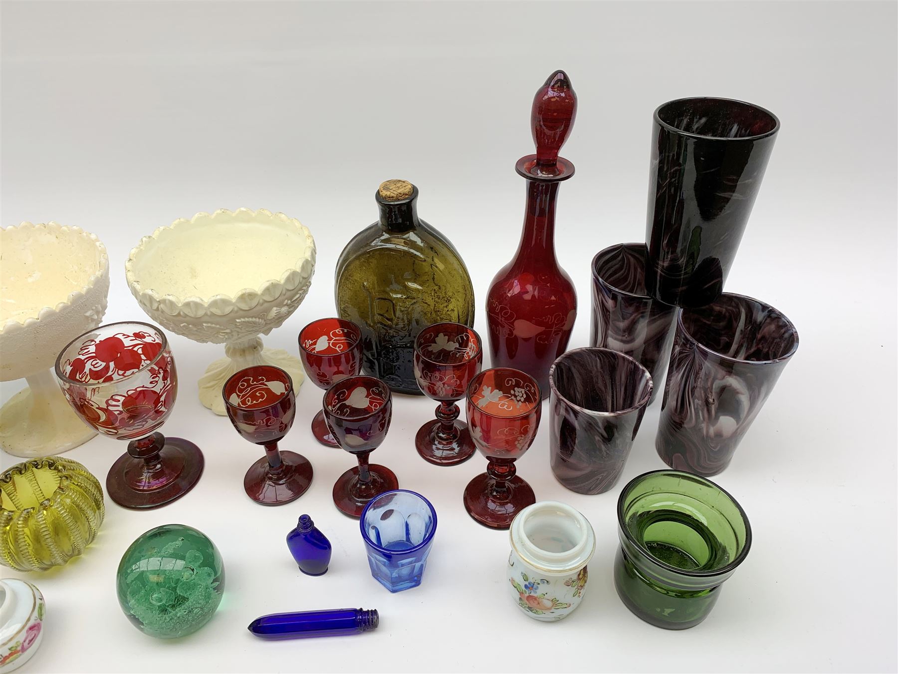 A group of Victorian glassware, to include Ruby flashed decanter and six glasses, decanter H25cm, five further drinking glasses with green bowls, a dump paperweight, and miniature painted milk glass teawares, two slag glass pedestal bowls, four slag glass tumblers, plus a small selection of later glassware, comprising a moulded glass bottle detailed 'Success to the Railroad', and an amber glass Isle of Man 1892 exhibition compressed tumbler. 