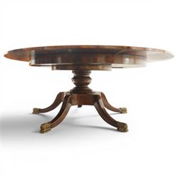 Theodore Alexander - Regency Revival figured mahogany 'Althorp Patent Jupe' extending dining table, the segmented circular top formed of six pull-out triangular divisions with inset fold-out leaves, raised on a large turned vasiform pedestal on a pentagonal platform base with ebonised stringing, terminating to five splayed supports with gilt metal acanthus scrolled feet, retailed by David Hick Interiors, Jersey