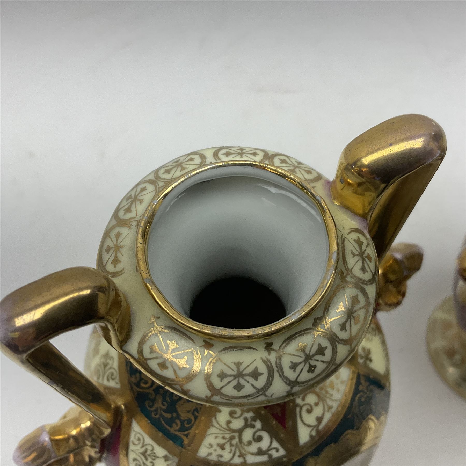 Pair of Vienna style twin handled urns and covers, decorated with figural scene on green, red and white ground with gilt highlights, stamped with beehive mark beneath, H25cm