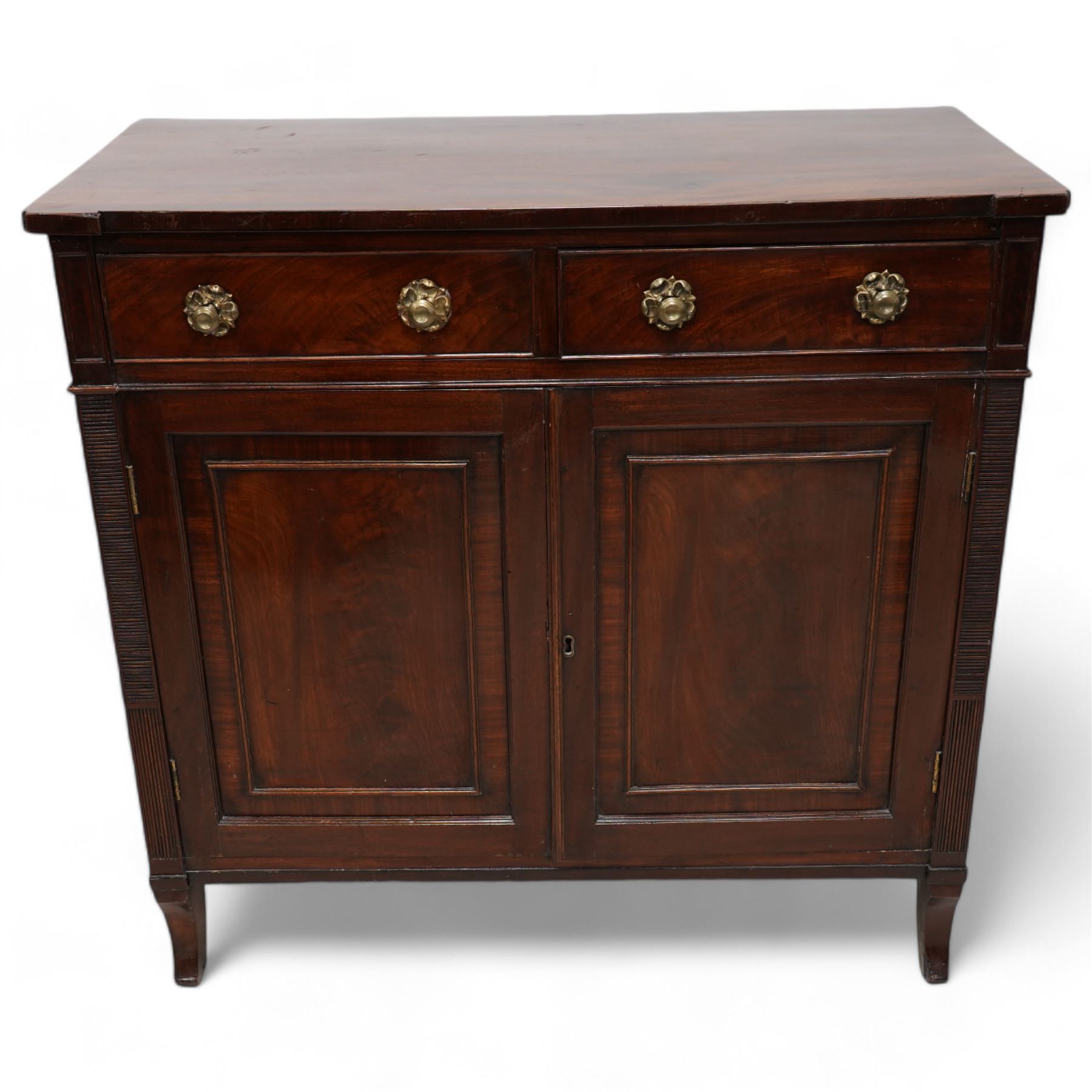 Regency mahogany cupboard, rectangular shaped top over two cock-beaded frieze drawers, fitted with brass Yorkshire rose pull handles, over two panelled and cross-banded cupboards, flanked by reeded uprights, raised on curved feet