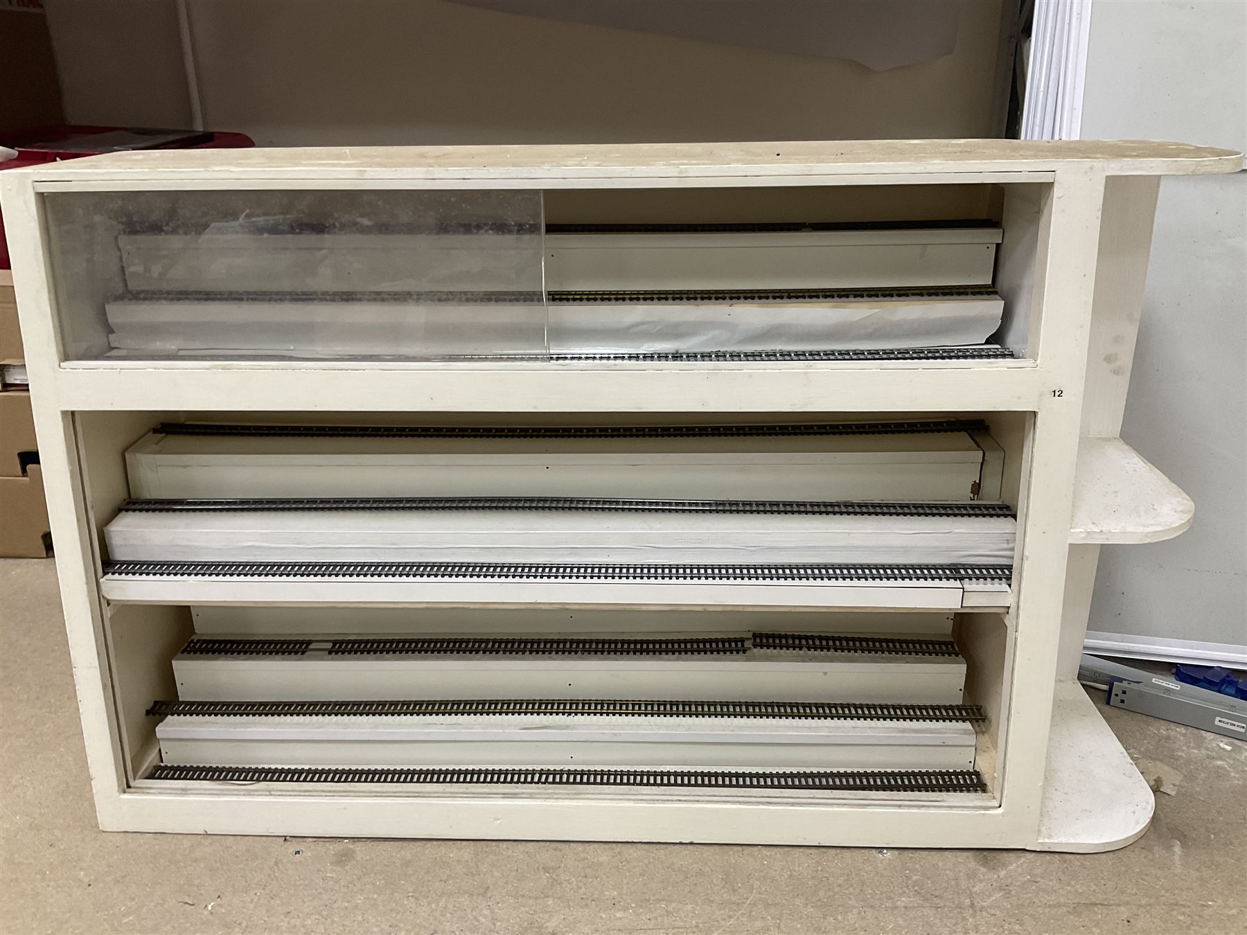 Six shelved cabinets for displaying ‘00’ gauge locomotives comprising plain plywood and white painted examples with track applied to various shelves, largest H63cm, W107cm, D27cm; Collection of tools for building model locomotives to include Weller PU-2D Soldering Pencil and Standard Tip Soldering Iron 20W/230V, Humbrol Modellers Airbrush, Power Supply Units and two wooden chests one of which housing a collection of tools including tweezers, scalping tools, wrenches etc 