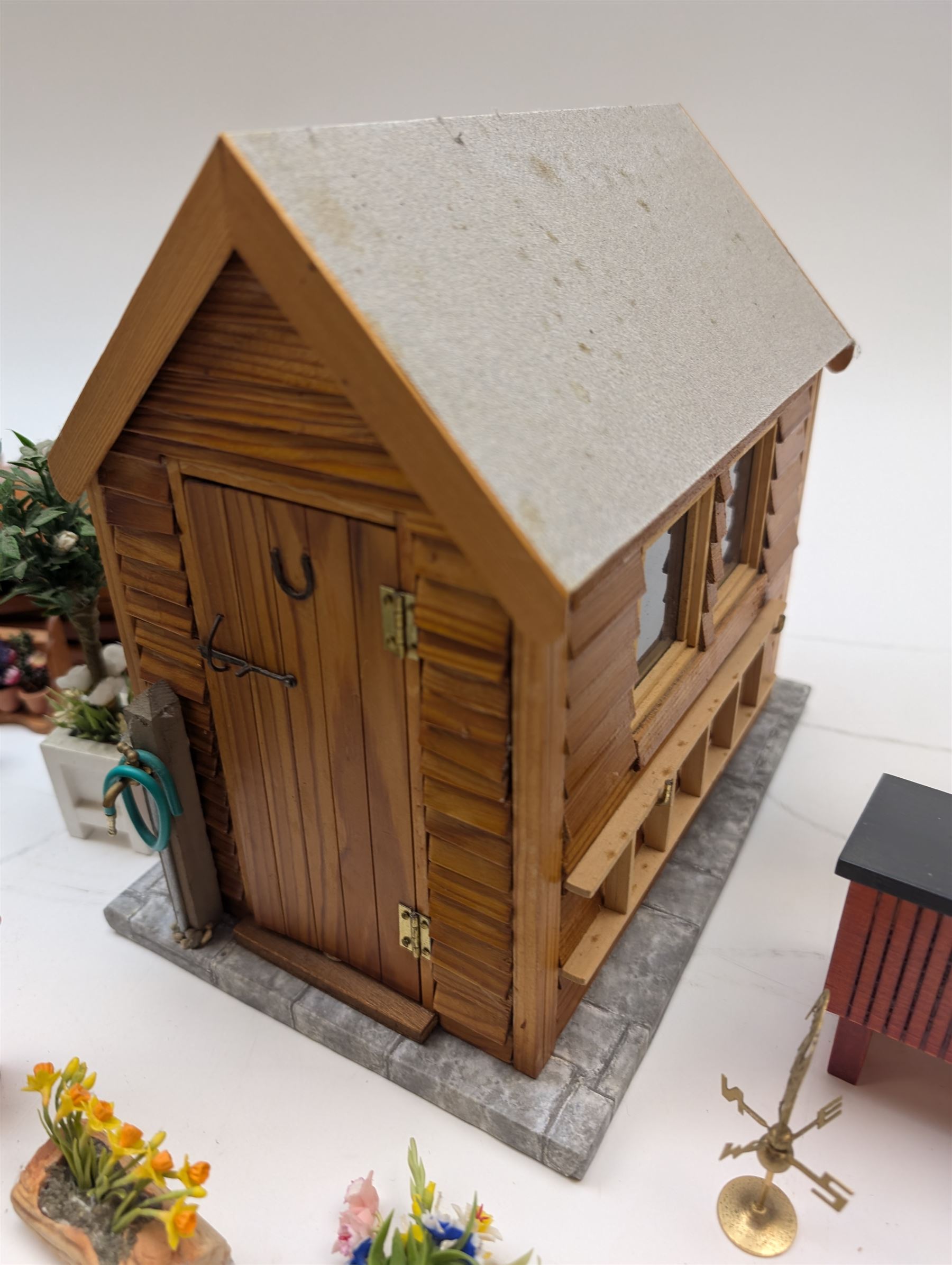 1:12 scale dolls house allotment and garden accessories, including wooden shed on a stone effect base, two vegetable patches, terracotta plant pots with flowers and foliage, stone effect plant pots, other planters, loose sunflowers, scarecrow, rabbit hutch, garden tools, fencing panels, etc 