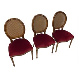 Set six French style walnut finish dining chairs, oval cane bergere backs over serpentine seats upholstered in red, flower head carved fluted supports
