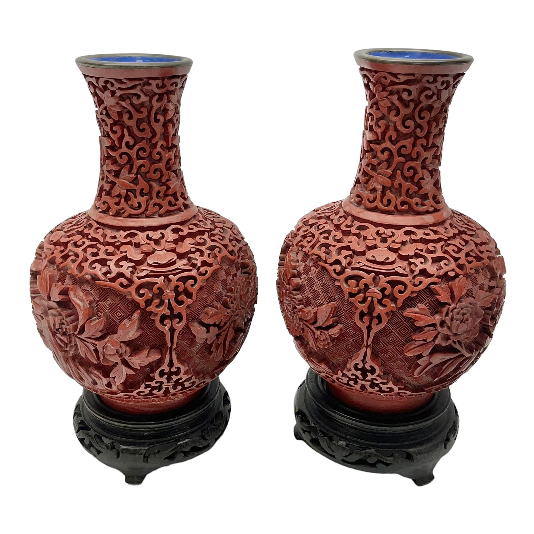 Pair of Chinese cinnabar lacquer vases, each of bulbous baluster form, carved with peonies and foo dogs amongst scrolls, with blue enamel interior and upon wooden bases, H20cm