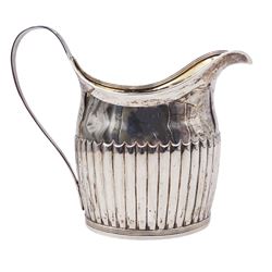 Large George III silver cream jug, of part fluted oval-helmet form, with engraved crest beneath lip, curved handle, and gilt interior, hallmarked William Bateman I, London 1816, including handle H4.5cm, approximate weight 11.20 ozt (348.6 grams)