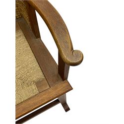 Reynold Eunson (1932–1978) for David Munro Kirkness, Kirkwall, Orkney - oak framed Orkney rocking chair, woven straw curved back, drop-in rush seat, the arm terminals with carved end scroll, on square tapering supports joined by plain stretchers, the front rail inscribed with makers marks