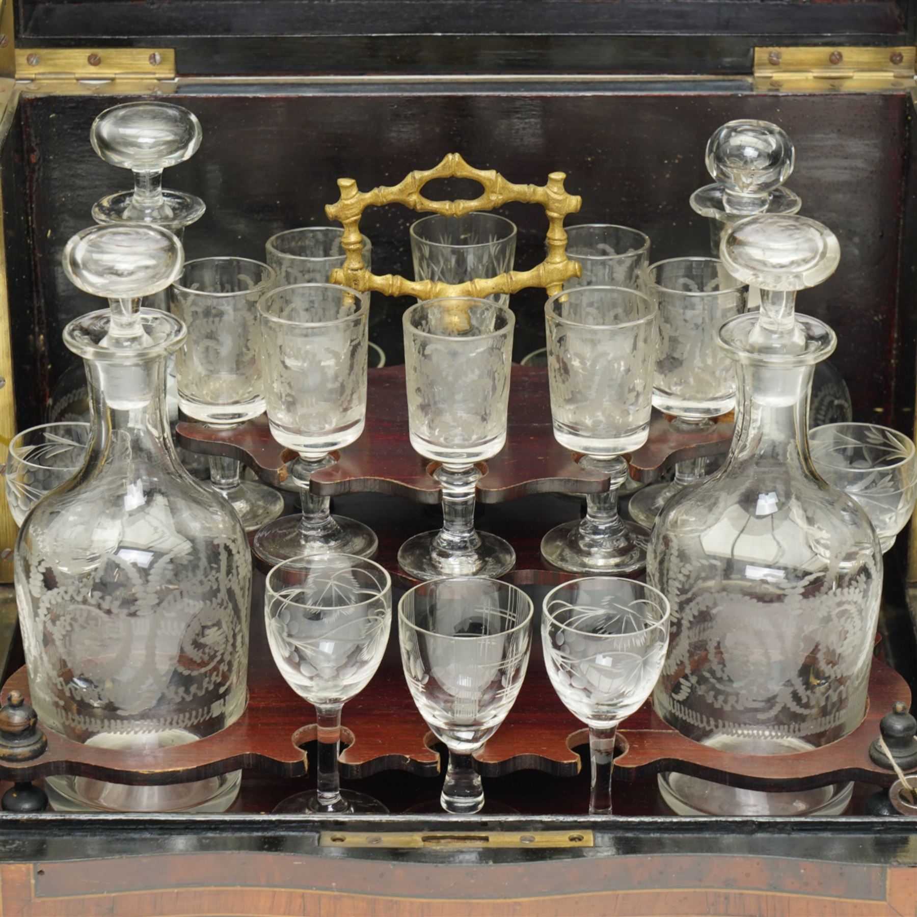 19th century French Boulle-style cave à liqueur or travelling decanter set, with musical mechanism playing carrara bonne de ay and Locked in the old Kent Road, the walnut box of serpentine front, the hinged lid with central brass and mother of pearl cartouche, with removable wooden tiered tray with gilt metal handle, containing four foliate etched glass decanters and sixteen glasses, H27cm