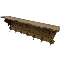 Oak wall hanging coat rack, shape lintel over panelled back carved with foliate S-scrolls, fitted with seven hooks
