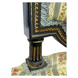 19th century French ebonised low chair, upholstered in floral striped fabric within a moulded frame with gilt line and foliate decoration, the seat of serpentine form, raised on turned fluted legs with toupie feet