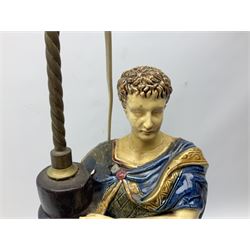 Composite table lamp modelled as a Roman Emperor donning blue robes, upon quatrefoil base modelled with rams heads and winged cherubs, H56cm excl fitting