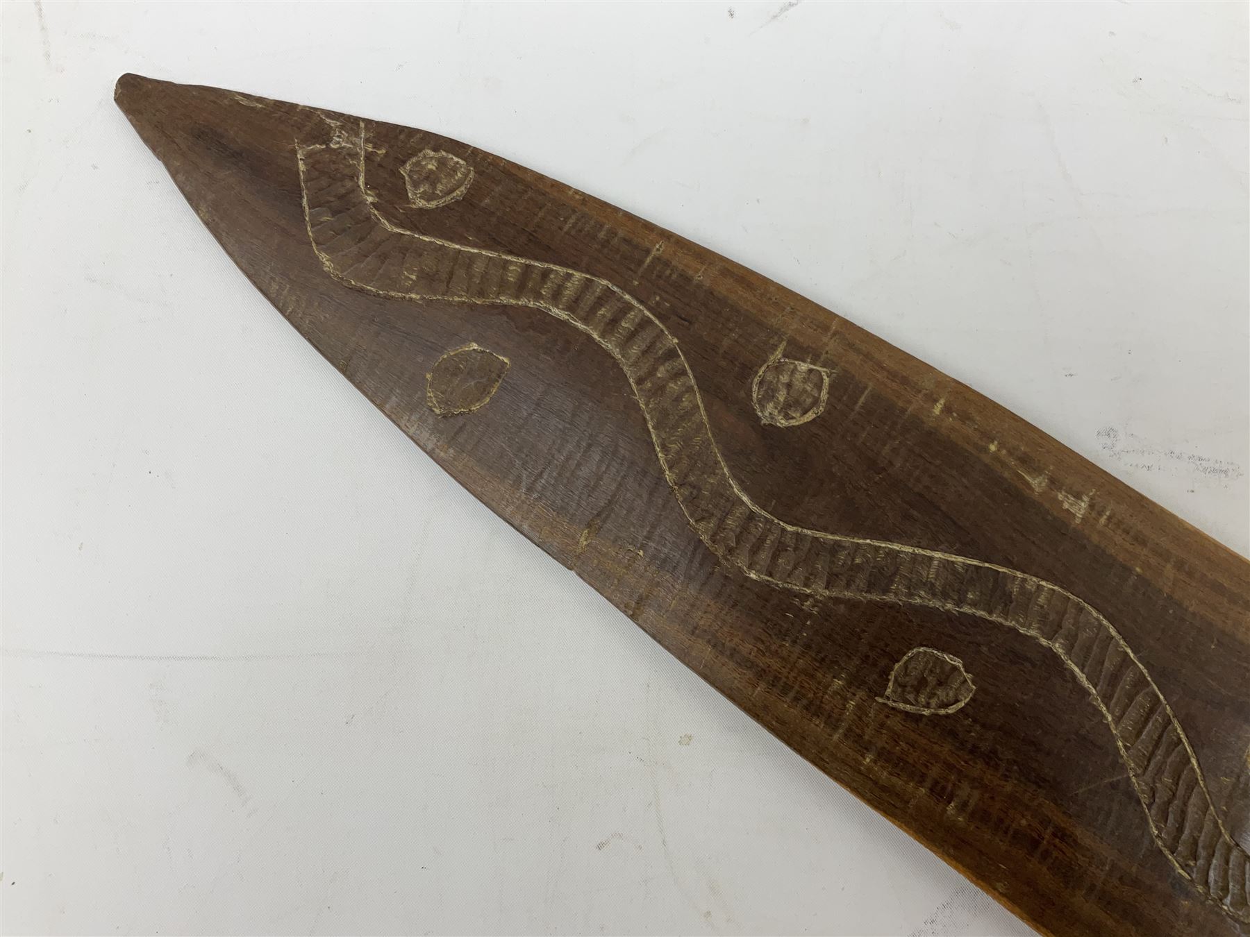 Australian aboriginal woomera spear thrower incised/carved with a wavy line and dots L69cm; and two boomerangs, one with carved geometric decoration (3)