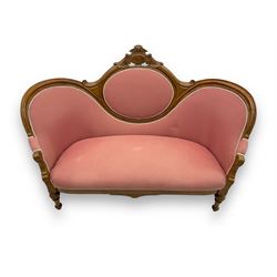 Late Victorian walnut framed double spoon back sofa, shaped crest rail with central carved medallion over curved back with pink upholstery, scrolling arms with additional carvings, on turned supports