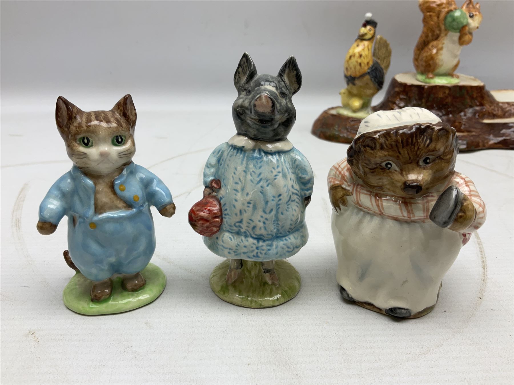 Seven Beswick Beatrix Potter figures, comprising Sally Henny Penny, Johnny Town-Mouse, Mrs Tiggy-Winkle, Mrs Tittlemouse, Tom Kitten, Pig-Wig and Squirrel Nutkin, together with a Beswick tree trunk display stand, stand L30cm