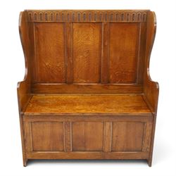 Early 20th century oak box settle, panelled back with arcaded carved rail, swept sides and arms, hinged seat with storage, panelled front