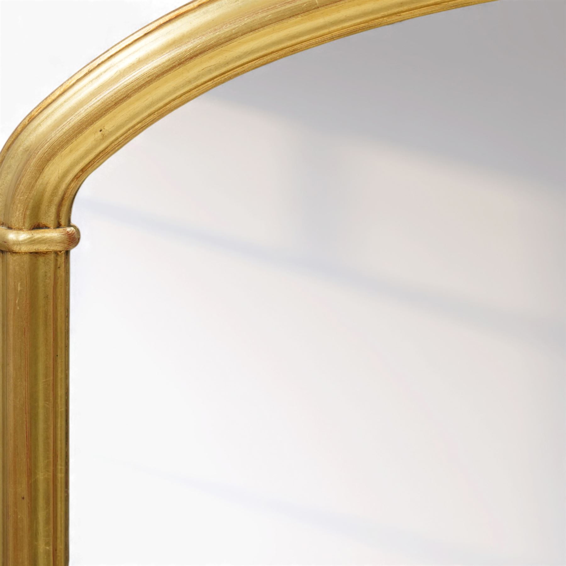 Contemporary large giltwood overmantel mirror, arched rectangular form with reeded moulded frame and stepped lower rail
