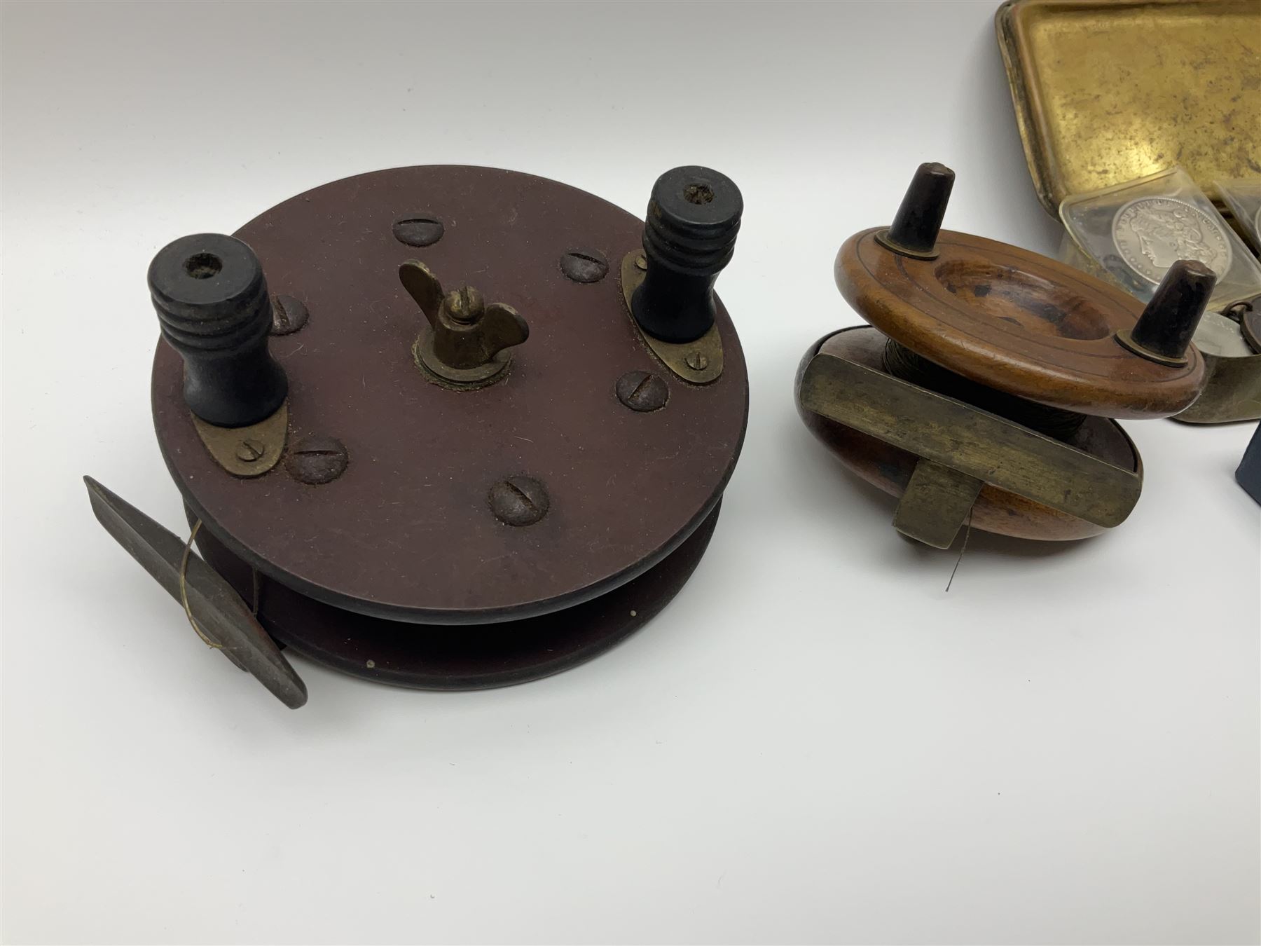 Six early 20th century fishing reels, to include wooden and brass examples, together with a leather powder flask, 1913 Christmas tin, Morgan dollar, Queen Victoria double florin and a collection of other coins, etc 