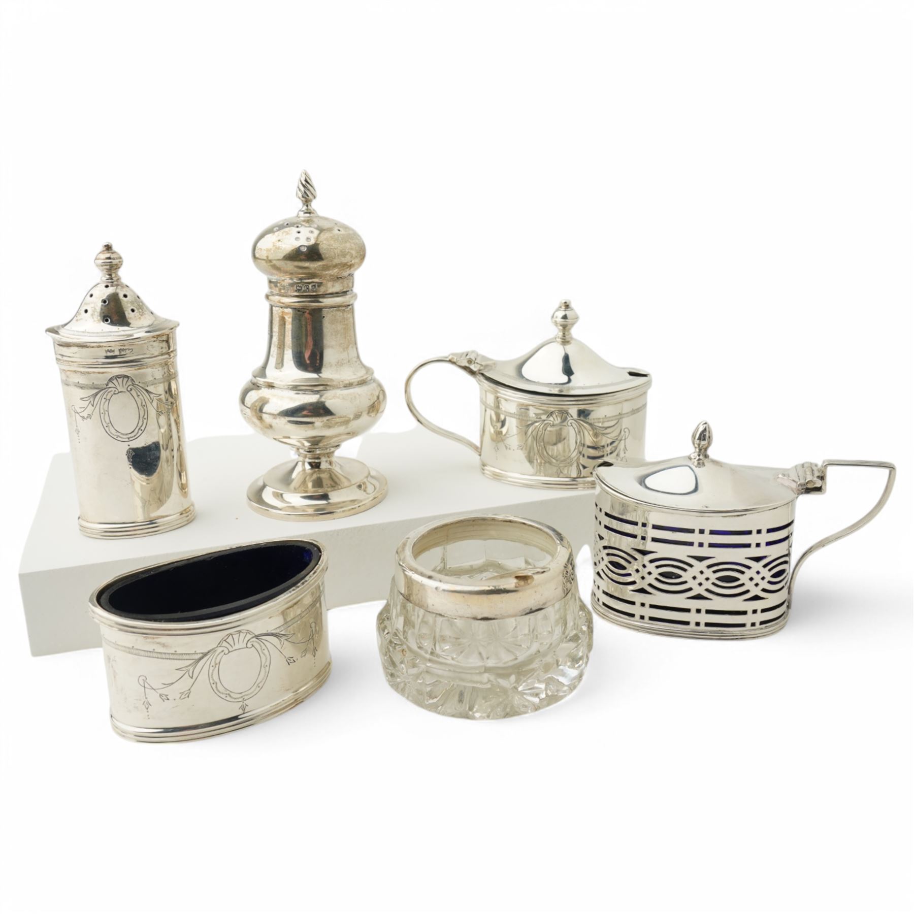 Silver three piece oval condiment set with engraved decoration Birmingham 1961, pierced silver mustard pot Chester 1901, silver pepperette and silver mounted glass salt