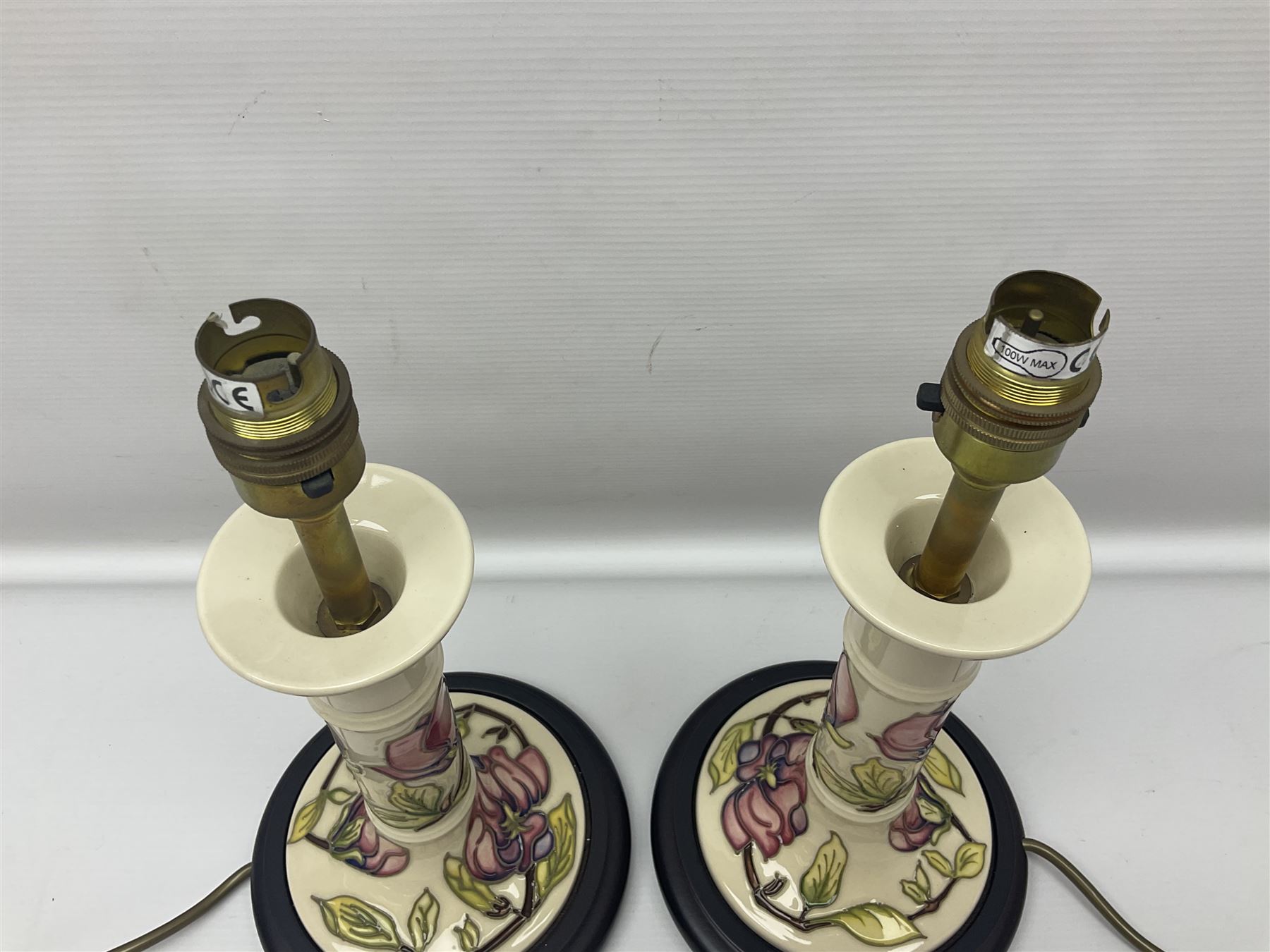 Pair of Moorcroft table lamps of candlestick form in magnolia pattern, with Moorcroft shades, H50cm 
