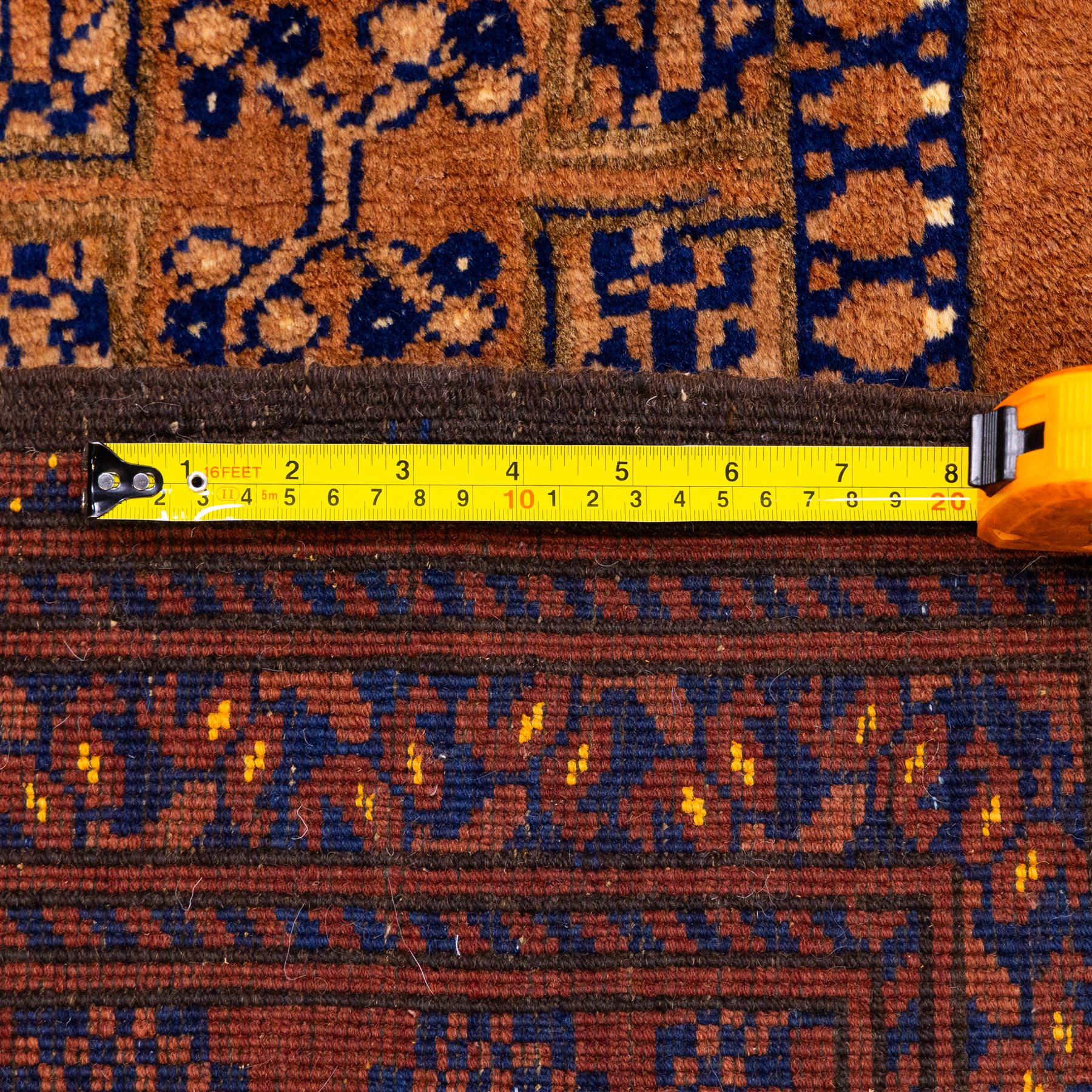 Pakistani Bokhara hand-knotted carpet, camel field decorated with rows of large tekke style octagonal guls enclosing stylized geometric motifs, interspersed with small stepped diamond devices within multiple geometric borders, with fringe ends 