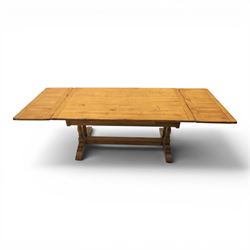 Traditional oak refectory dining table, fitted with draw leaves to either end extending to 257cm, on twin turned and block supports united by a stretcher, terminating in shaped trestle feet