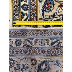 Central Persian Kashan hand-knotted carpet, ivory field with an all-over design of scrolling vines, lotus palmettes, and rosettes in shades of blue and brown within a blue ground border of palmettes and arabesques between multiple guard stripes, 
348 cm x 246cm