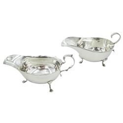 Two early 20th century silver sauce boats, the first example with flying scroll handle, upon three hoot feet, hallmarked Walker & Hall, Sheffield 1916, the second with shaped rim and acanthus capped scroll handle, upon three pad feet, hallmarked Henry Bourne, Birmingham 1903, approximate total silver weight 6.65 ozt (207 grams)