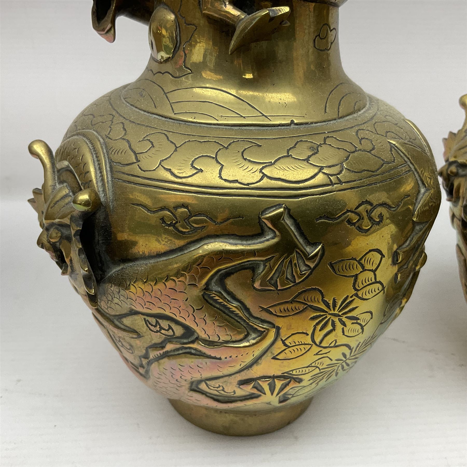 Pair of Chinese brass vases, of ovoid form with elongated neck and fluted rim, decorated in high relief with a dragon chasing a flaming pearl around the neck, the body with dragons, birds and buildings, with character marks beneath, H25cm