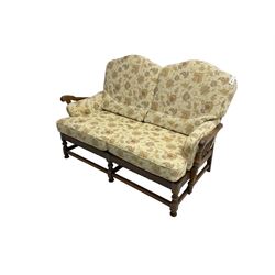 Ercol elm two seat sofa (W155cm, D100cm, H100cm), and matching footstool (60cm x 60cm, H44cm), loose cushions upholstered in floral pattern fabric