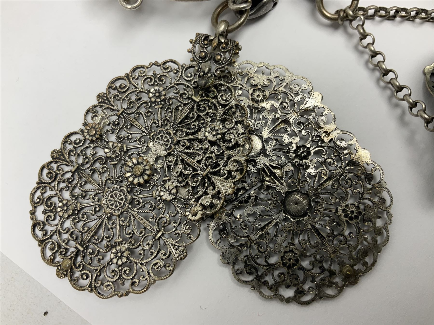 19th century continental silver plated chatelaine, the main body flanked with winged mythical beasts and central soldier slaying a dragon supporting three suspended items to include velvet lined small basket and long clasped filigree chain, together with a thimble