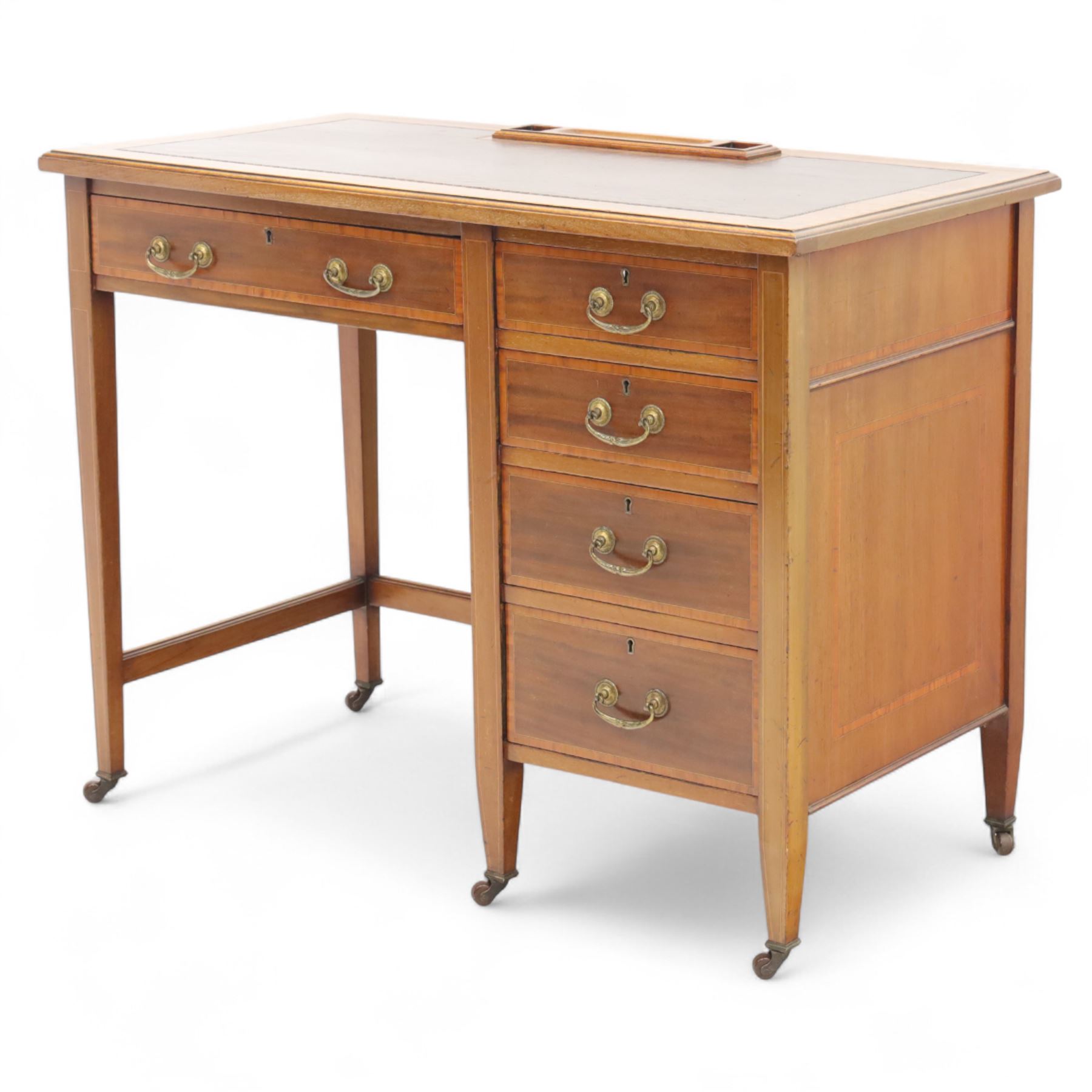 Early 20th century Edwardian mahogany single pedestal writing desk, the crossbanded rectangular top inset with brown leather, fitted with five drawers with brass swan neck handles, upon square tapering supports terminating in brass castors