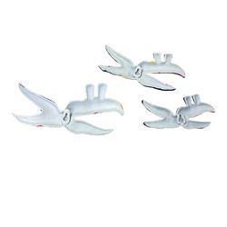 Three cast iron Guinness toucans in flight, together with two cast iron hooks